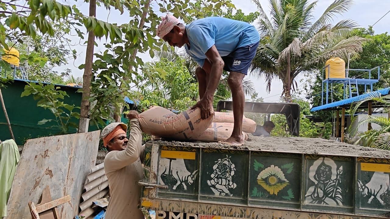 Workers unload cement bags from a tractor trailer.