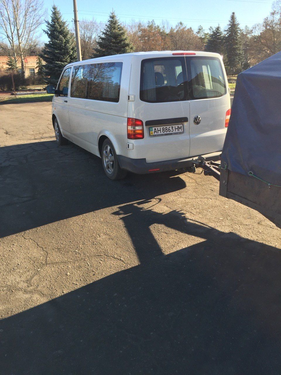 A white van with Ukrainian plates towing a covered trailer.