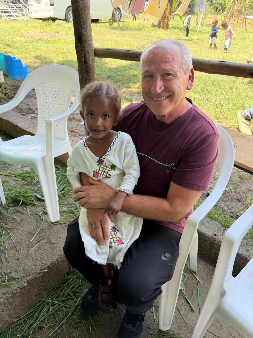 A Love in Deed volunteer smiles with a little girl on his lap.